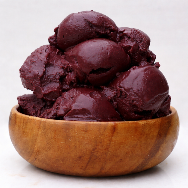 large wooden acai bowl filled with vibrant frozen scoopable acai 